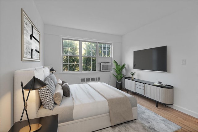 bedroom featuring radiator, wood finished floors, baseboards, and cooling unit
