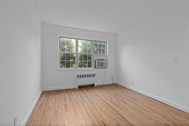 spare room with cooling unit, baseboards, hardwood / wood-style floors, and radiator heating unit