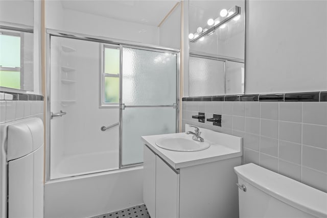 bathroom featuring vanity, tile walls, shower / bath combination with glass door, and toilet