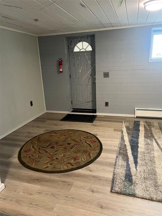 entryway with wooden walls, baseboards, a baseboard radiator, and wood finished floors