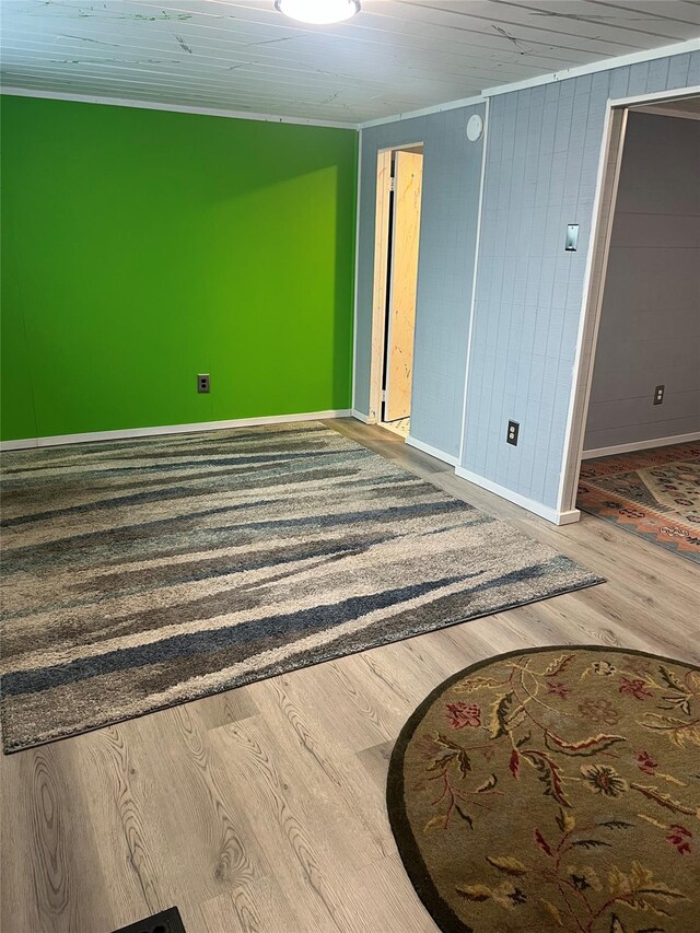 spare room featuring baseboards, ornamental molding, and wood finished floors