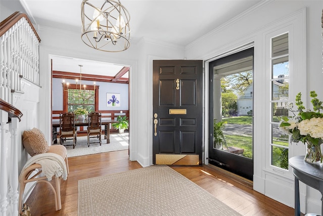 foyer featuring an inviting chandelier, crown molding, and wood finished floors