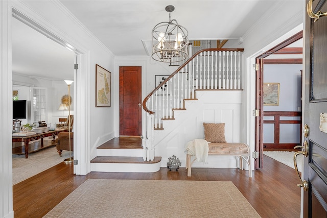 entrance foyer with ornamental molding, stairs, a notable chandelier, and dark wood finished floors