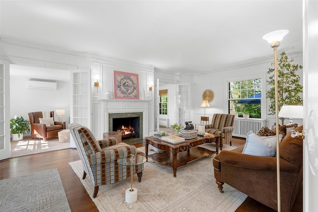 living area with crown molding, a high end fireplace, light wood finished floors, and an AC wall unit