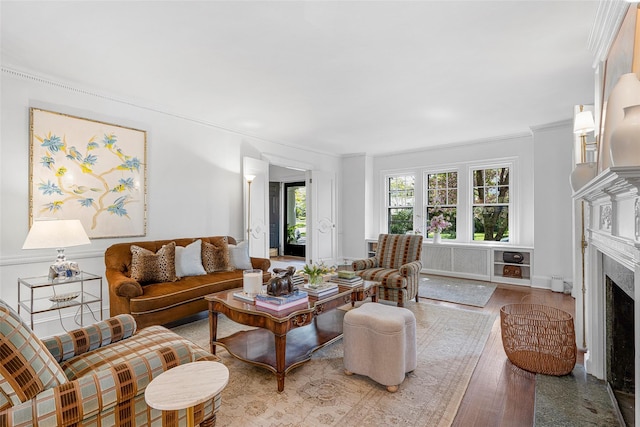living area with crown molding, wood finished floors, and a fireplace