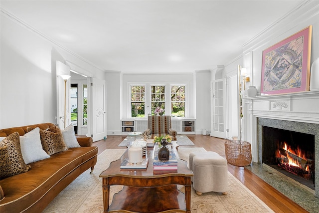 living room with crown molding, baseboards, a fireplace, and wood finished floors