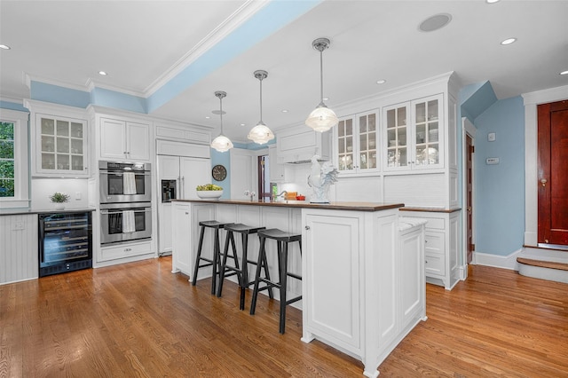 kitchen featuring white cabinetry, wine cooler, ornamental molding, and stainless steel double oven