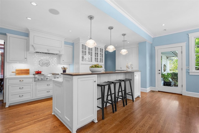 kitchen featuring light wood-type flooring, white cabinetry, tasteful backsplash, and a kitchen bar
