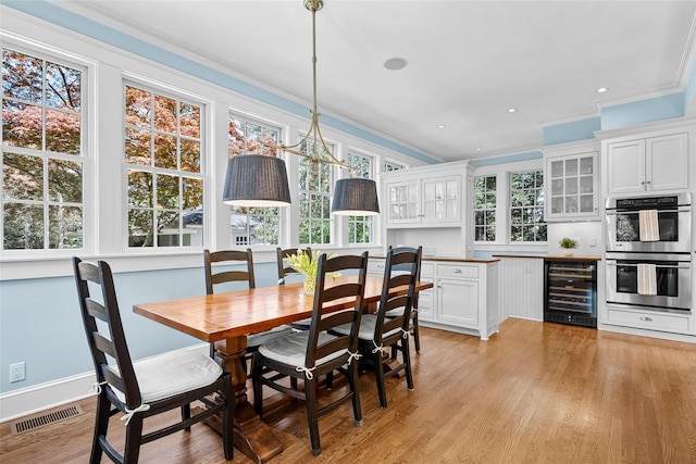 dining area with visible vents, ornamental molding, beverage cooler, recessed lighting, and light wood-type flooring