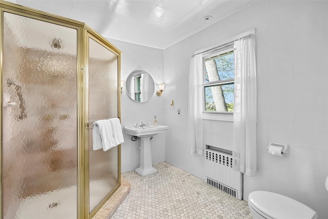 bathroom with toilet, radiator, tile walls, and a shower stall