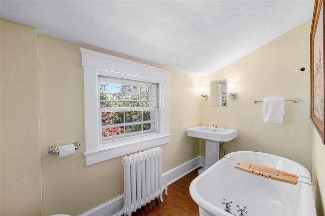 full bathroom featuring baseboards, wood finished floors, radiator heating unit, and a soaking tub