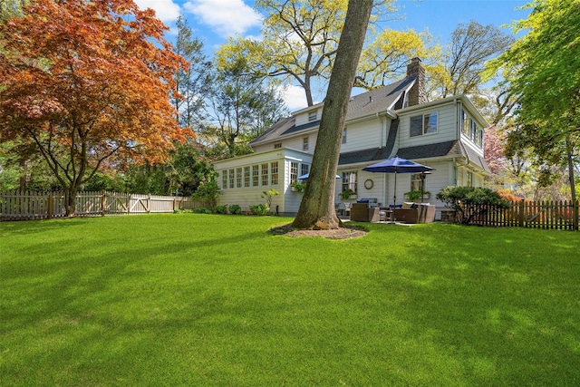 back of house with a lawn and a fenced backyard
