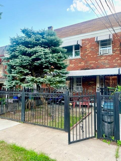 3231 Grace Ave, Bronx, NY 10469 - view of front of home featuring covered porch, brick siding, cooling unit, and a fenced front yard