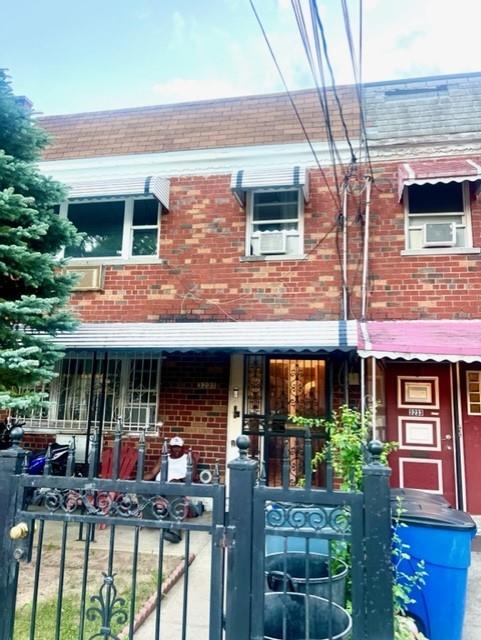 3231 Grace Ave, Bronx, NY 10469 - view of front of house featuring a porch, a fenced front yard, a gate, brick siding, and cooling unit