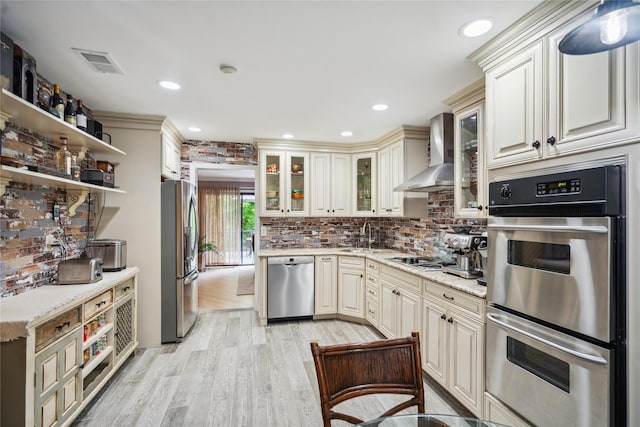 185 Old Pond Ct Unit 185, Jericho, NY 11753 - kitchen featuring appliances with stainless steel finishes, wall chimney exhaust hood, cream cabinetry, light wood-style floors, and recessed lighting