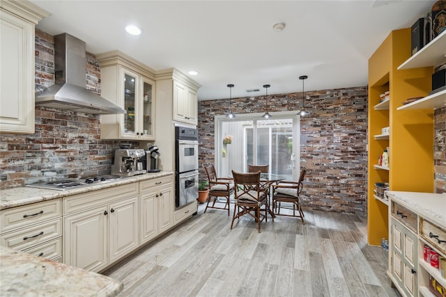 185 Old Pond Ct Unit 185, Jericho, NY 11753 - kitchen with wall chimney exhaust hood, cream cabinets, cooktop, light wood finished floors, and hanging light fixtures
