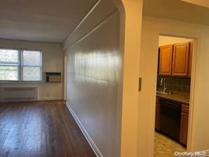 hall with light wood-style floors, baseboards, and radiator heating unit