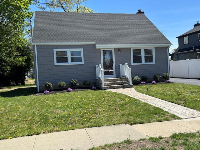 view of front facade with a front yard and roof with shingles