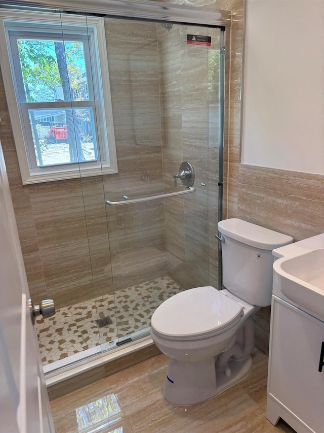 full bathroom featuring vanity, tile walls, a stall shower, and toilet
