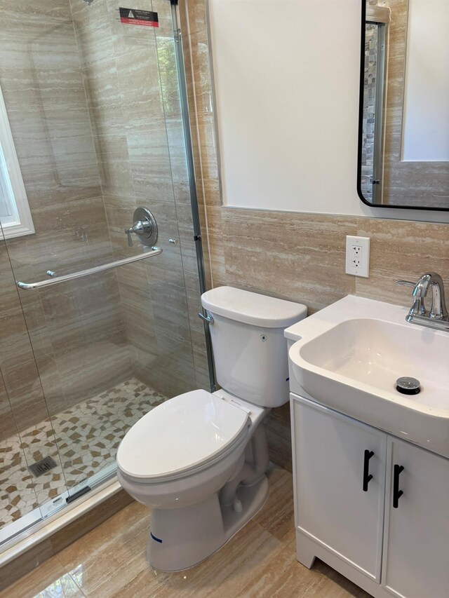 full bathroom with tile walls, a shower stall, wood finished floors, vanity, and toilet