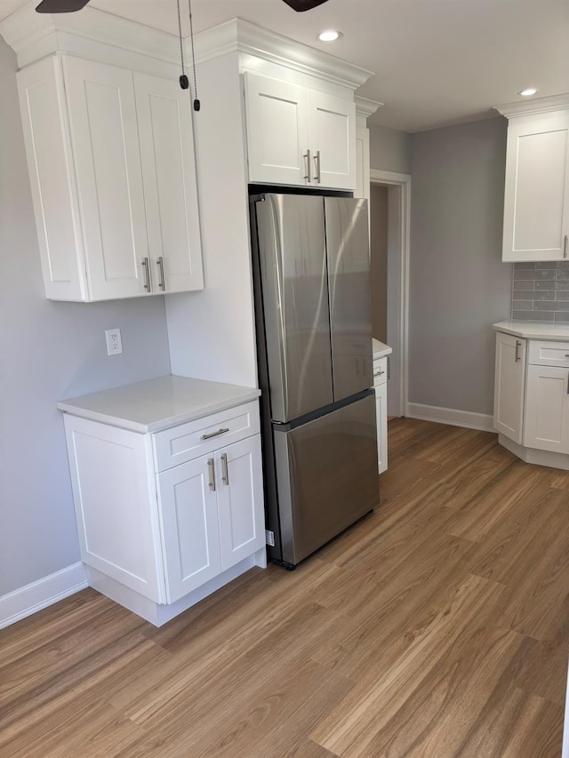 kitchen with light wood finished floors, light countertops, freestanding refrigerator, recessed lighting, and baseboards