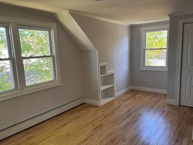 additional living space with baseboards, baseboard heating, and light wood-type flooring