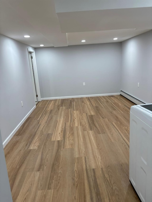 finished below grade area featuring recessed lighting, washer / dryer, wood finished floors, and baseboard heating