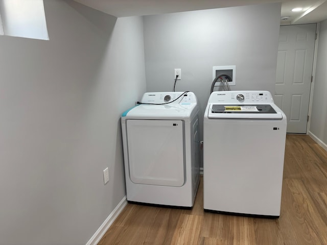 clothes washing area featuring washing machine and clothes dryer, baseboards, and wood finished floors