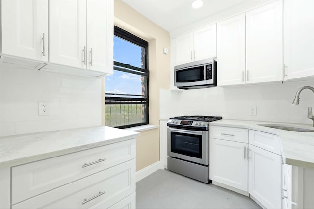 25-40 Union St Unit 6B, Flushing, NY 11354 - kitchen with backsplash, appliances with stainless steel finishes, a sink, light stone counters, and white cabinets