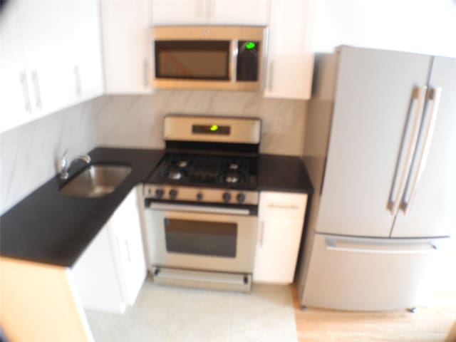 237 Madison St, Brooklyn, NY 11216 - kitchen featuring stainless steel appliances, a sink, dark countertops, and white cabinetry