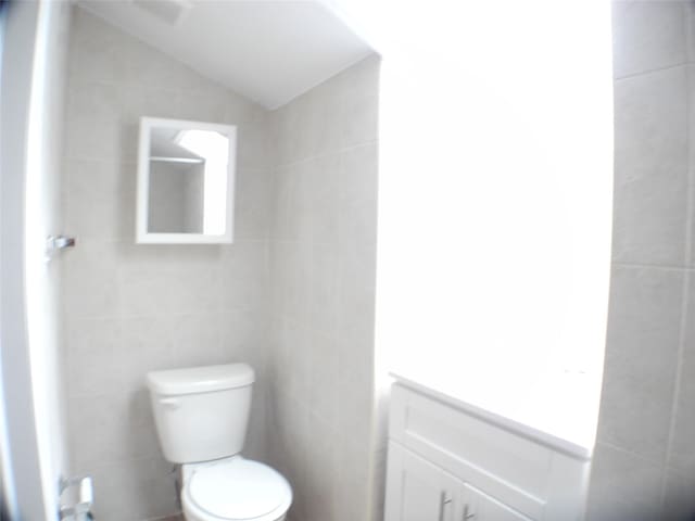 237 Madison St, Brooklyn, NY 11216 - half bathroom featuring tile walls, vanity, toilet, and vaulted ceiling