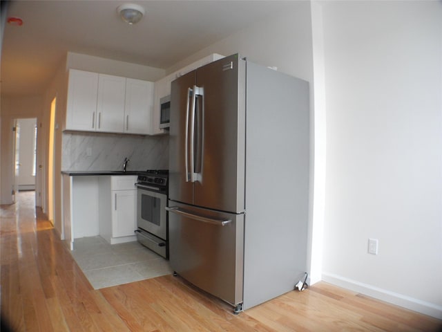 237 Madison St, Brooklyn, NY 11216 - kitchen with appliances with stainless steel finishes, light wood-style flooring, white cabinetry, and tasteful backsplash