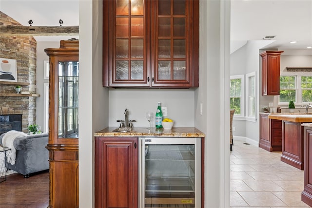 1465 Ackerly Pond Ln, Southold, NY 11971 - indoor wet bar featuring wine cooler, light tile patterned floors, and a stone fireplace