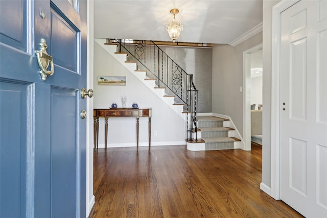 entryway with stairway, a chandelier, wood finished floors, baseboards, and ornamental molding