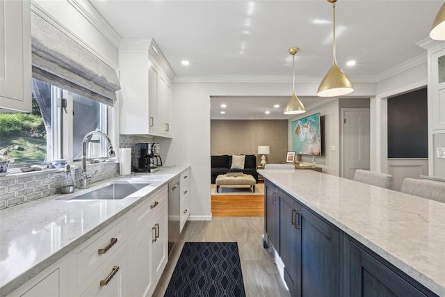 kitchen with a sink, decorative backsplash, white cabinets, pendant lighting, and recessed lighting