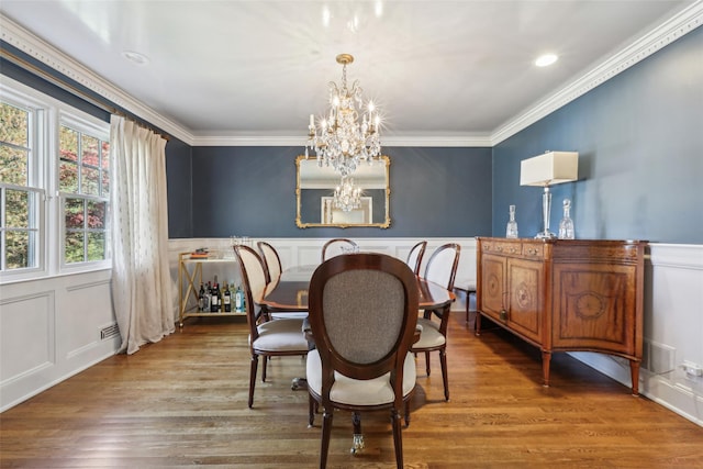dining space with a decorative wall, a chandelier, ornamental molding, wood finished floors, and a wainscoted wall