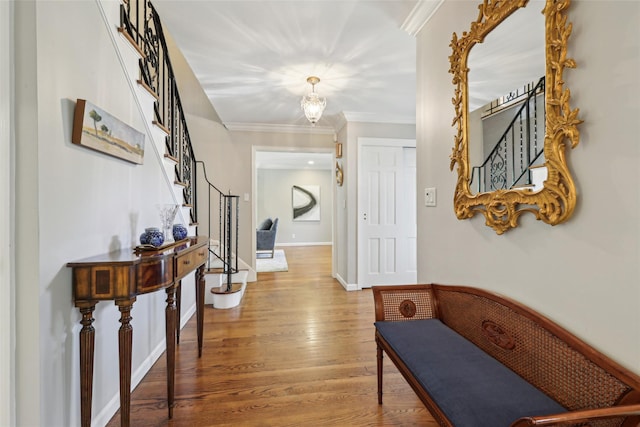 hall featuring light wood finished floors, stairs, crown molding, and baseboards