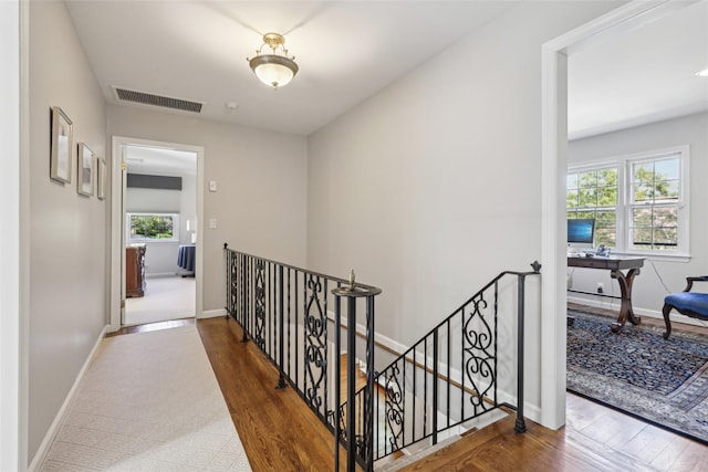 corridor featuring an upstairs landing, wood finished floors, and baseboards