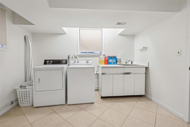 clothes washing area with separate washer and dryer, light tile patterned floors, baseboards, and cabinet space