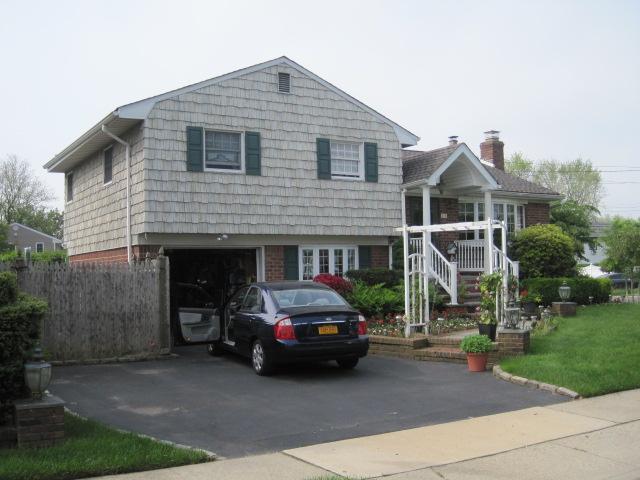 tri-level home with an attached garage, driveway, and a chimney