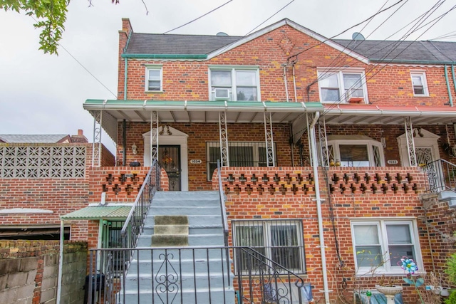 townhome / multi-family property featuring brick siding, stairway, a gate, covered porch, and fence private yard