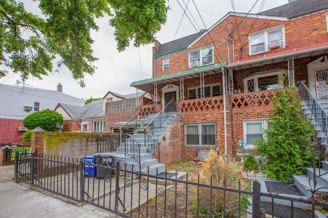 multi unit property with stairs, a fenced front yard, and brick siding