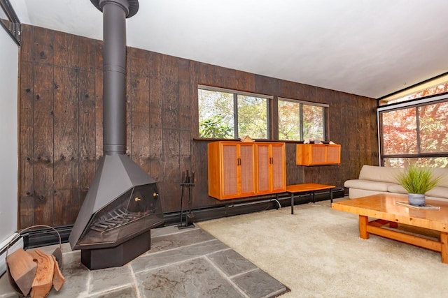 living room featuring a wood stove, wooden walls, and baseboard heating