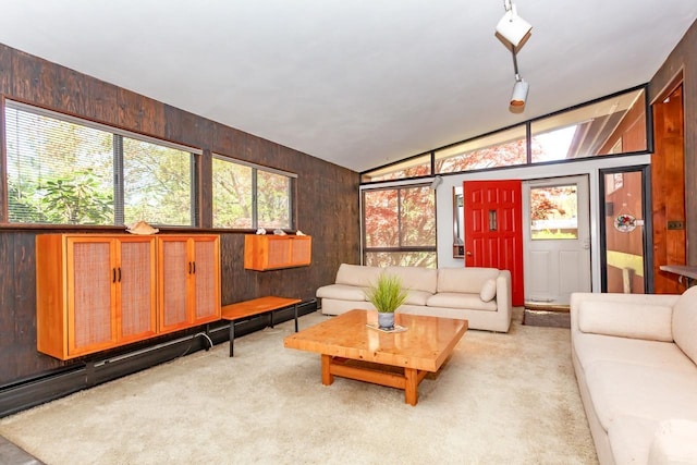 living area featuring wooden walls, lofted ceiling, and light colored carpet