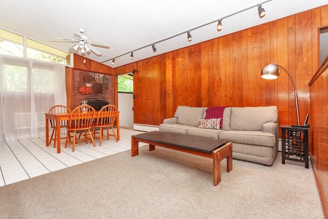 living area with a ceiling fan, wood walls, rail lighting, carpet floors, and tile patterned floors