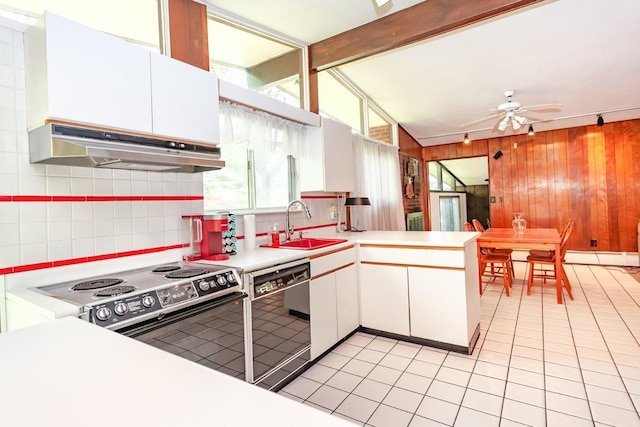 kitchen with wood walls, a peninsula, decorative backsplash, under cabinet range hood, and black appliances