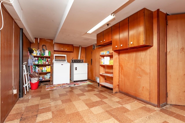 clothes washing area featuring light floors, cabinet space, and washing machine and clothes dryer