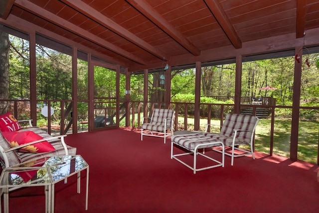 sunroom with carpet floors, lofted ceiling with beams, and wooden ceiling