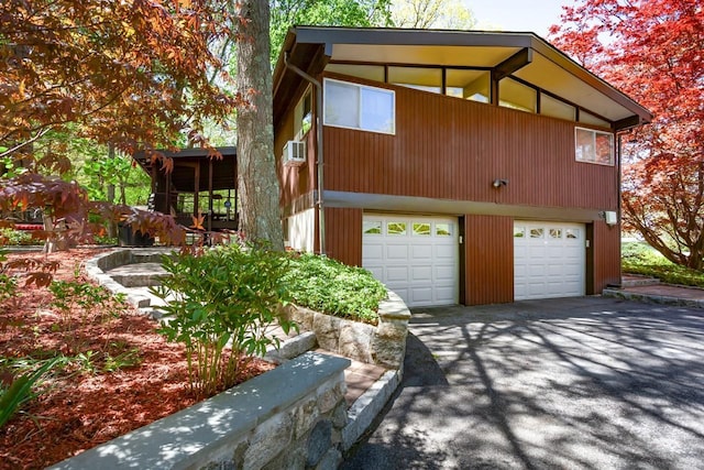 view of side of home with an attached garage and aphalt driveway
