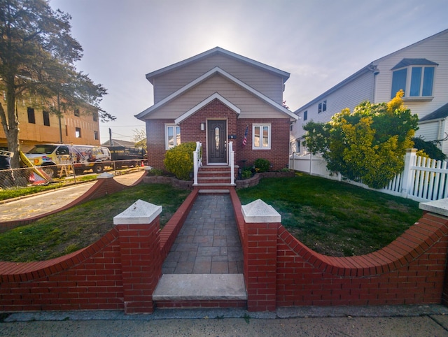 bungalow-style house with brick siding, fence private yard, and a front yard